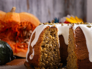 A delicious pumpkin pound cake on a rustic wooden table, surrounded by pumpkins.
