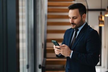 Portrait of handsome well dressed businessman using phone
