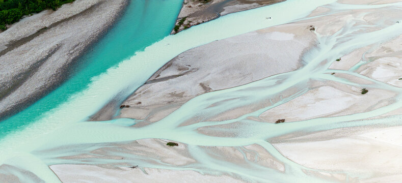 Aerial view of the braided Tagliamento River, with turquoise water flowing through gravel beds. The river's braided pattern creates a unique landscape.
