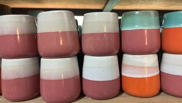 Shelves filled with an assortment of vibrant, handcrafted ceramic mugs