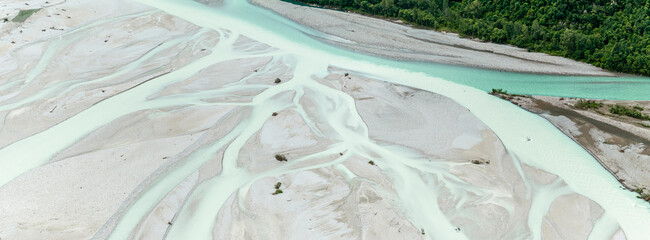 Aerial view of the braided river, showing its pale turquoise waters and gravel banks. Iconic Italian river Tagliamento, Friuli, Carnia, Italy. The river flows from the top right to the bottom left.