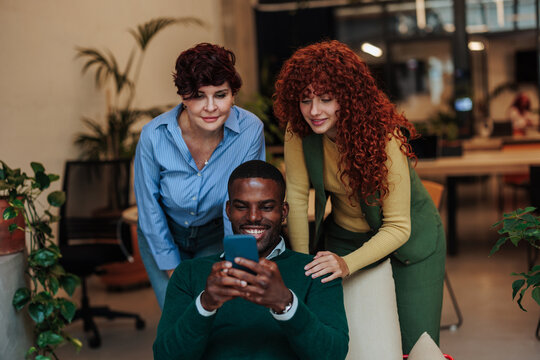 Smiling business team using mobile phone in modern office