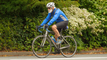 Fototapeta premium Inspiring image of a vibrant elderly man enjoying a bike ride, showcasing health and activity in golden years. Perfect for themes of active aging, well-being, and senior fitness
