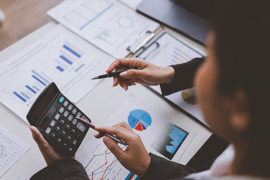 Businesswomen calculating and analyzing financial charts and graphs