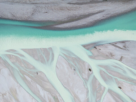 Aerial view of the iconic Italian river Tagliamento, Friuli,  Italy. The turquoise water flows through gravel beds, creating a braided pattern. The river's unique morphology is visible from above.