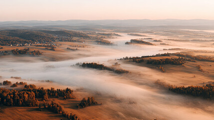 Fototapeta premium Morning fog flows over rural fields and forest hills at sunrise