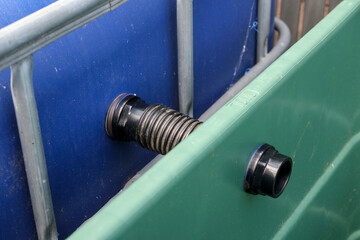 Rainwater overflow system connecting two water storage tanks. The green tank collects excess from...