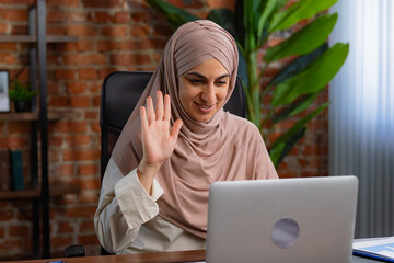 Smiling Woman in Hijab Waving During a Virtual Meeting