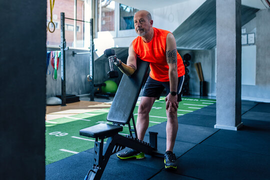 Person with prosthetic arm exercising with dumbbell at gym