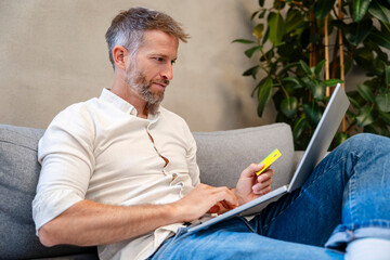 Confident person paying online with credit card using laptop at home