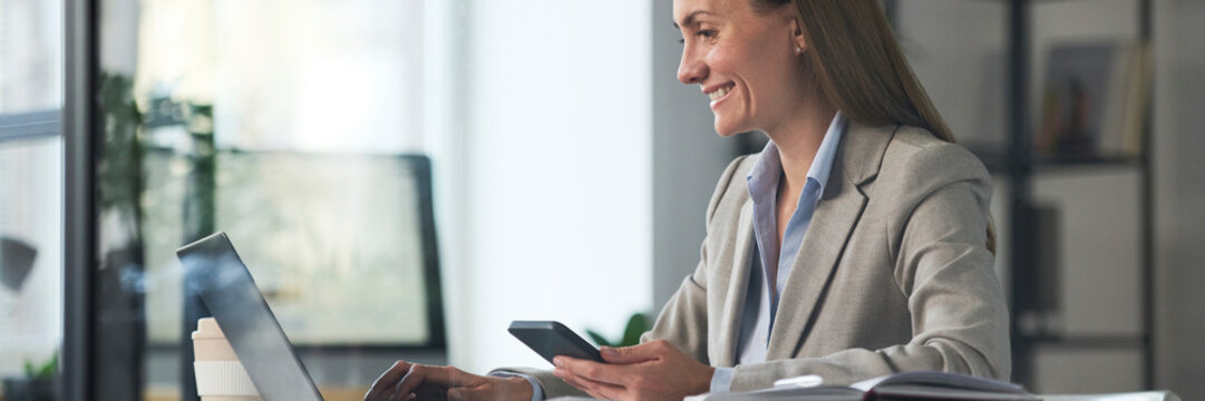 Cheerful manager working on laptop and video call in office