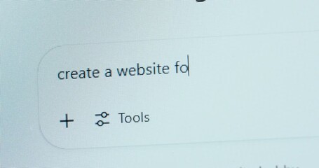 A user types “create a website for my busniess” into an AI chatbot, showing a spelling mistake—highlighting growing dependence on AI and declining attention to detail.