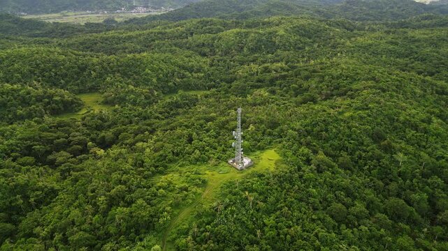 Aerial drone shot of a telecommunications cell tower amid lush tropical island greenery and rolling hills at Catanduanes, Bicol, Philippines.