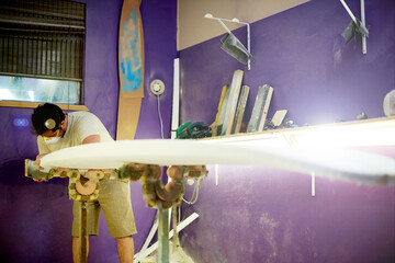 Man, workshop and manufacturing with surfboard, design or career for water sport equipment in mask for safety. Person, process and ppe gear with tools, inspection or quality assurance at surf factory