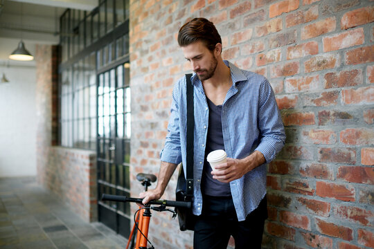 Businessman, coffee and waiting with bicycle in hallway for local commute or travel in office building. Man, traveler or creative employee with bike for eco friendly transportation or ride to work