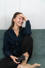 Woman laughing while playing videogames on sofa at home