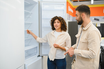 Couple discussing refrigerator options in appliance store