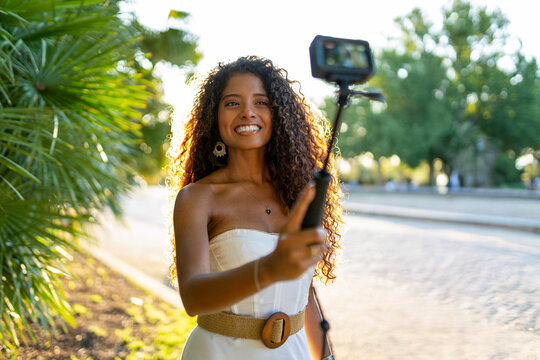 Latin influencer creating content with action camera on selfie stick