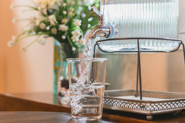 Water is poured into a glass from a manual water dispenser.