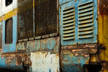 Close-up of an old locomotive and old carriages on a decommissioned railway, the paint cracked, peeled and rusted.