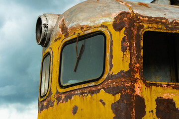 Close-up of an old locomotive and old carriages on a decommissioned railway, the paint cracked, peeled and rusted.