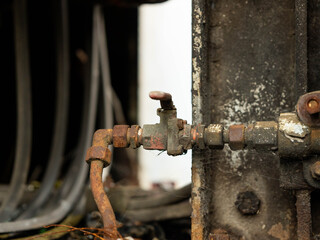 Close-up of an old locomotive and old carriages on a decommissioned railway, the paint cracked, peeled and rusted.