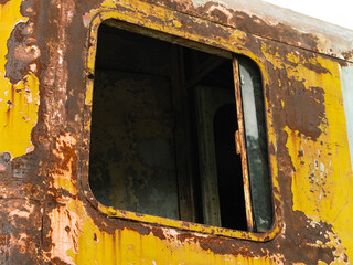 Close-up of an old locomotive and old carriages on a decommissioned railway, the paint cracked, peeled and rusted.