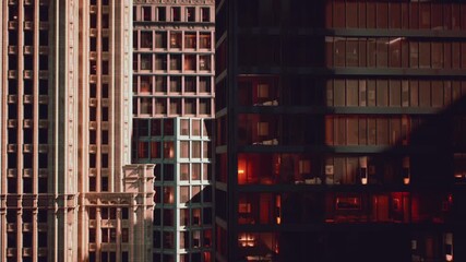 Sunlight illuminates the facades of modern and historic buildings, showcasing urban architectural diversity. Shadows create a dramatic effect during late afternoon in the city.