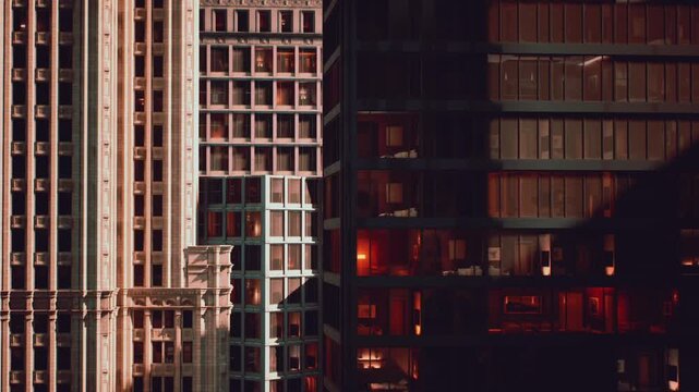 Sunlight illuminates the facades of modern and historic buildings, showcasing urban architectural diversity. Shadows create a dramatic effect during late afternoon in the city.