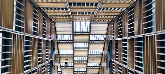 A striking low-angle, wide shot looking directly up into a modern building's atrium and large indoor space, showcasing an intricate ceiling and skylight design.