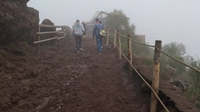 15.10.2024 Volcanic Landscape of Mt. Vesuvius in Italy. Hikers explore a misty volcanic trail on a cloudy day in a unique natural landscape. A group of hikers walks along a rocky, mist-covered path. 