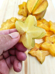 Hand Holding Bright Yellow Starfruit Pieces