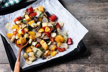 Roasted vegetables on a baking tray on wooden table