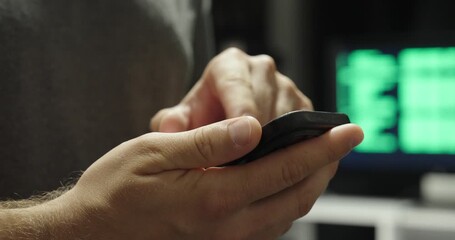 Close-up of a hand holding a smartphone using AI, with a display in the background showing AI code - Powered by Adobe