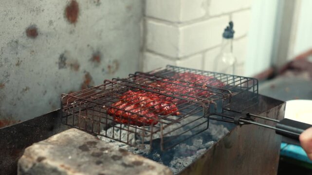 Traditional lula kebab cooking over hot embers on grill grate