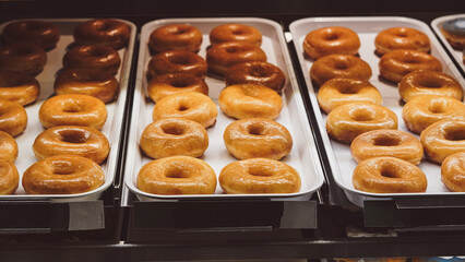 Sweet frosted donuts in glass showcase inside bright modern pastry boutique