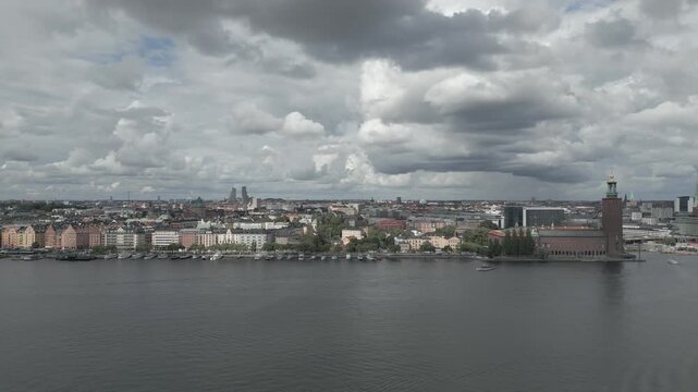 Aerial view of Stockholm City Hall with its prominent tower stands beside the still water under a sky heavy with clouds, Stockholm, Sweden.