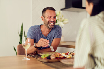 Man Smiling and Enjoying a Meal Together With a Friend Indoors