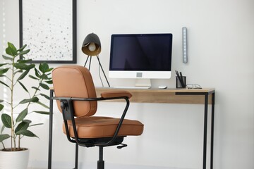 Stylish workplace with wooden desk, lamp and computer indoors