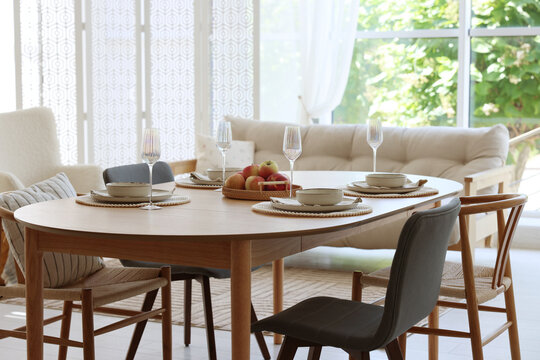 Beautiful table setting, chairs and decor in dining room. Interior design