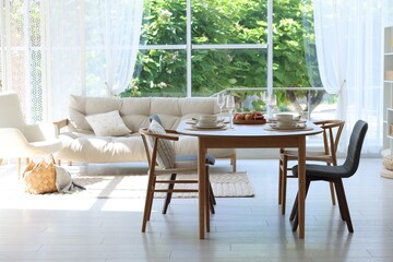 Beautiful table setting, chairs and decor in dining room. Interior design