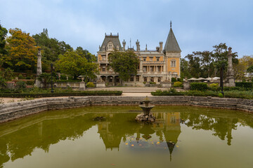Massandra Palace of Emperor Alexander III. Historic mansion with intricate architecture stands behind a serene pond, reflecting its majestic facade. Yalta, Crimea - September 30, 2019