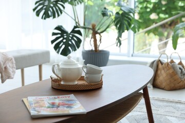 Teapot, cups and magazines on coffee table in dining room