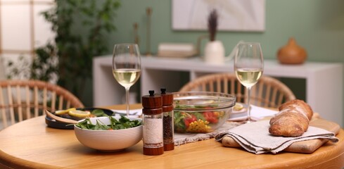 Dinner table with tasty food and white wine indoors