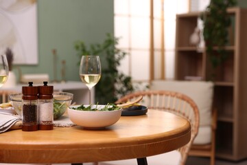 Bowl of salad, white wine and spices on table indoors