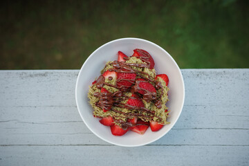 Homemade Dubai chocolate strawberry dessert with kataifi, pistachio paste, milk chocolate and fresh strawberries. Top view, vertical photo. Street food desserts and sweets. Copy space for text.