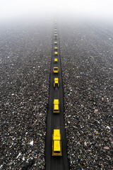 Aerial view of yellow landfill compactors on a road amidst garbage. Concept of waste management, pollution, environmental issues.