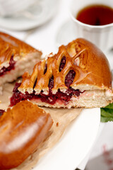 Warm cherry pie slice with rich filling on white plate, red napkin and cup of tea nearby. Captures cozy homemade moment, perfect for food stories.