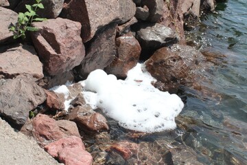 Foamy water at the edge of a rocky lake shore
