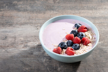 Healthy smoothie bowl with berries on wooden table. Copy space